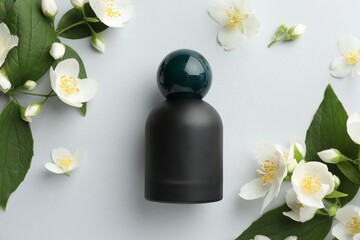 Bottle of perfume and jasmine flowers on light background, flat lay