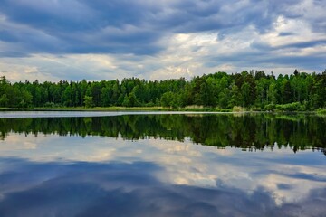 A peaceful lake reflecting the forest and cloudy sky