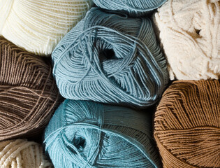 A collection of yarn balls in muted shades of blue, brown and light beige.