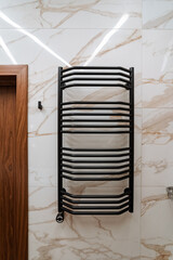 In a beautifully designed bathroom, a sleek and elegant black towel rack is proudly hanging on a...