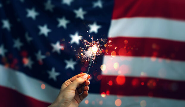 Woman holding Sparklers on American Flag background. Independence day United States. Celebration 4th of July - Patriotic Holiday.