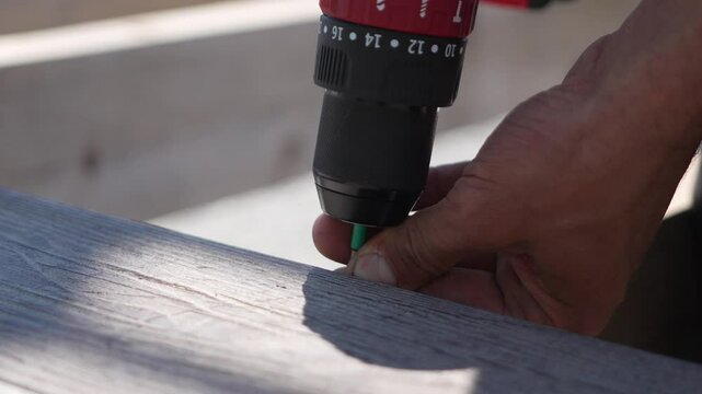 Hands Building Wood installing screw on composite deck board