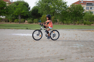 Young girl riding bicycle wearing helmet and protections in a park