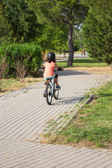 Girl riding bicycle wearing helmet and protections in a park