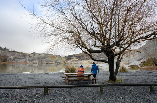 Couple sitting on the picnic bench by Blue Lake. St Bathans. Central Otago. South Island.