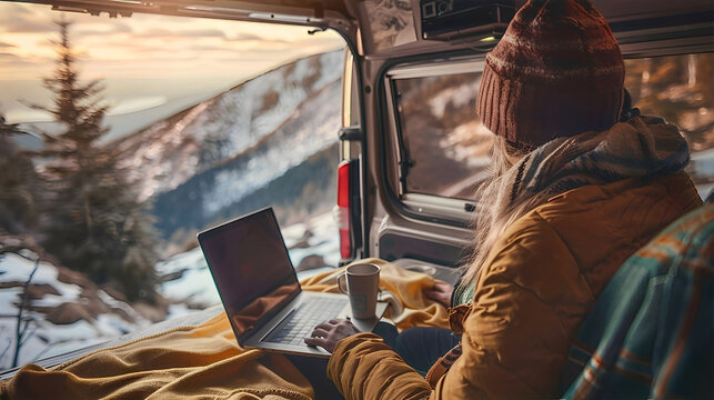 Woman working on laptop in cozy camper with open back door, scenic mountains, forest view outside, cup of coffee on the side, warm morning light, boho travel style. Freelancer, remote work - Powered by Adobe