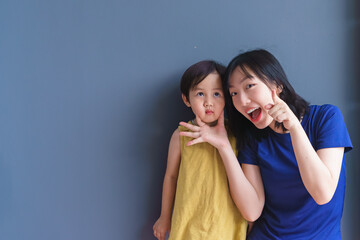 Joyful interaction between a child and an adult in a casual setting with a gray background,...