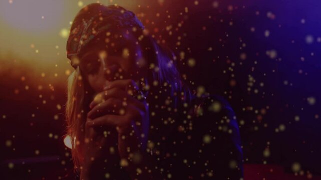 Singer bringing mic and singing under orange blue lights with gold particles drifting for music