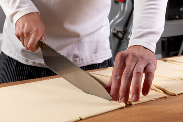 Pastry chef cutting puff pastry for croissants.