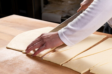 Pastry chef cutting puff pastry for croissants.