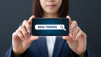 Woman in Blue Suit Holding Smartphone Showing 2026 Trends Search