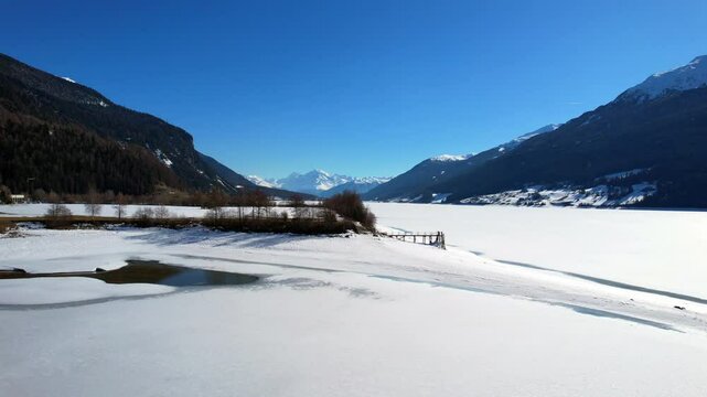 Lake Reschen - Vinschgau, South Tyrol - side view of the frozen lake with a view of the Ortler mountain range