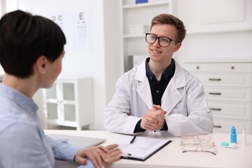 Obraz premium Ophthalmologist consulting woman at white table in clinic