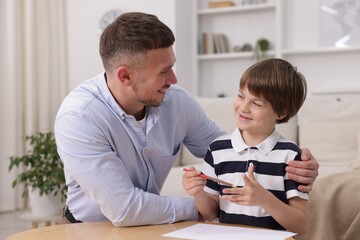 Fototapeta premium Father teaching his son to draw at table indoors