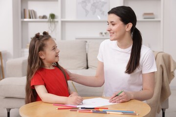 Obraz premium Mother teaching her daughter to draw at table indoors