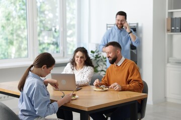 Obraz premium Colleagues eating and chatting during lunch break in office