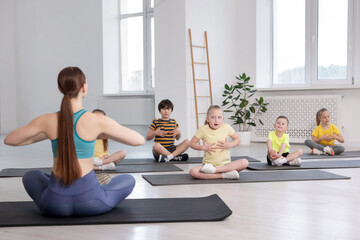 Fototapeta premium Group of children practicing yoga with coach on mats in class