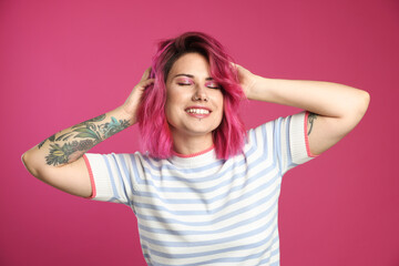 Beautiful woman with bright dyed hair on pink background