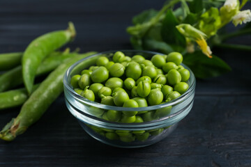Fresh ripe green peas on black wooden table, closeup