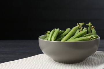 Fresh ripe green peas on black wooden table, closeup. Space for text