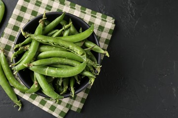 Fresh ripe green peas on black table, top view. Space for text