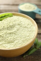 Protein powder and fresh pea pods on wooden table, closeup