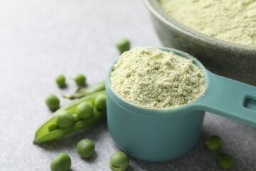 Protein powder and fresh green peas on light grey table, closeup