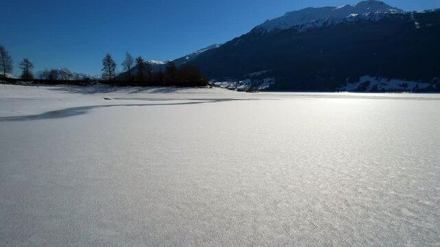 Reschen lake - Vinschgau, South Tyrol - speed aerial shot over the frozen lake just above the ground