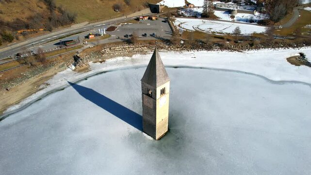 Church tower of Reschen - Vinschgau, South Tyrol - rotating aerial photograph from a great height above the frozen lake with a downward view of the tower top
