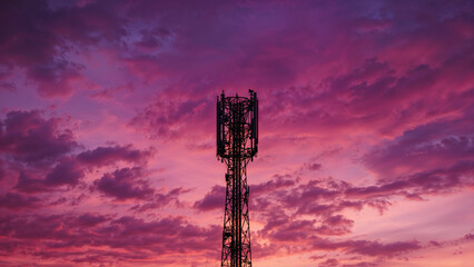 Fototapeta premium Cell Tower Silhouette Against Dramatic Purple Sunset Sky