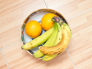 Bananas and oranges on a plate.