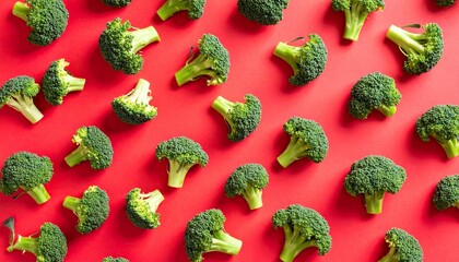 Fresh broccoli florets arranged neatly on a vibrant red background