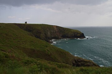 beautiful irish coastline with old defense tower, cliffs and atlantic ocean, ireland, ardmore cliffwalk