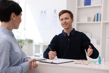 Ophthalmologist consulting woman at white table in clinic