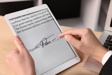 Electronic signature. Man using tablet at wooden table, closeup