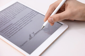 Electronic signature. Man using stylus and tablet at white table, closeup