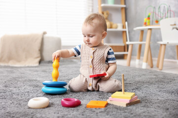 Cute little baby playing with toys in room