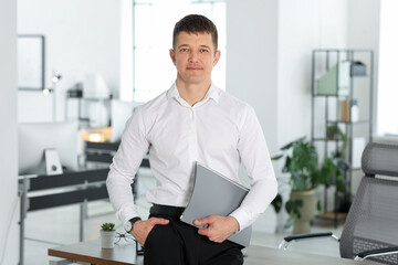 Fototapeta premium Portrait of handsome man with folder in office