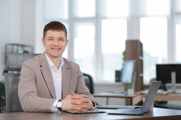 Portrait of handsome man at desk in office. Space for text