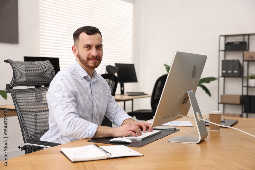 Poster man working on computer at desk in office