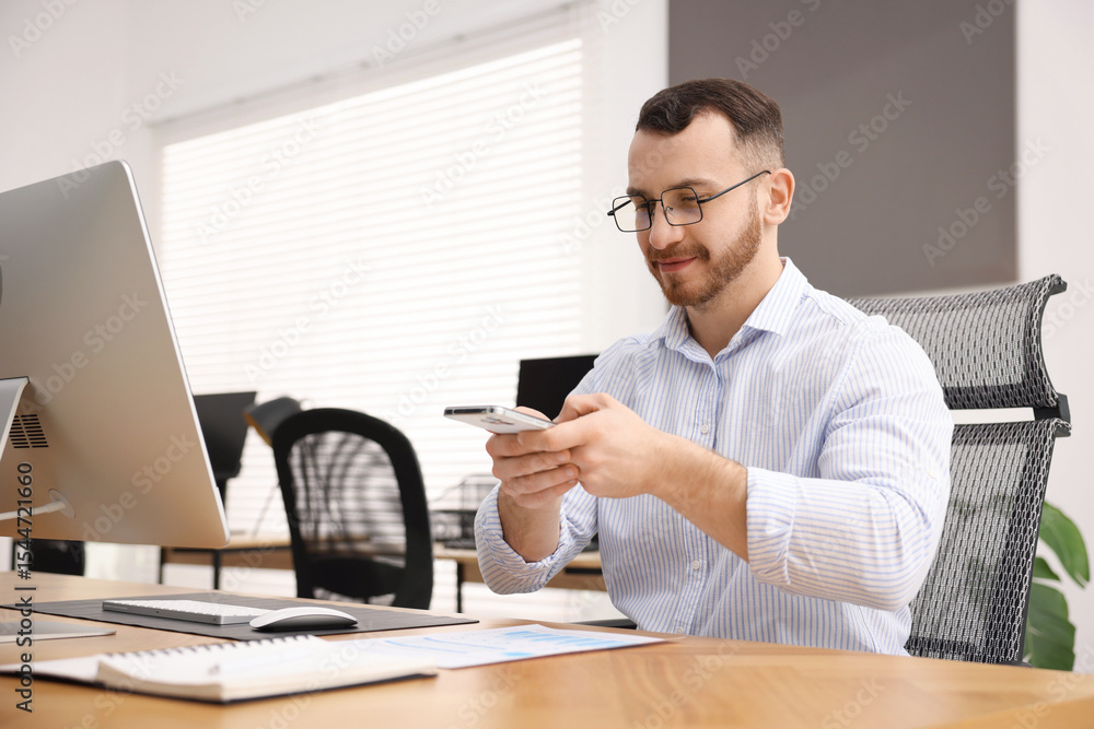 Poster man taking photo of document using scanning app on smartphone at desk in office