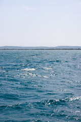 Kitesurfing in Rosas, Costa Brava, with choppy sea and beach in the background
