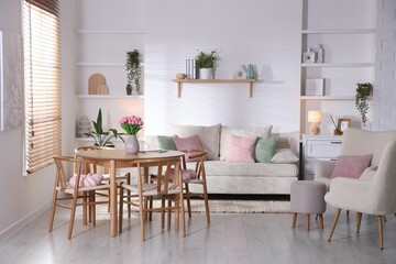 Stylish dining table with chairs and comfortable sofa in room. Interior design