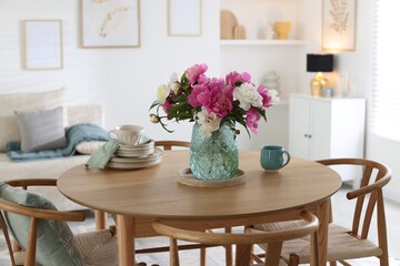 Dining table with beautiful flowers and dishware in room. Interior design