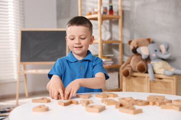 Dyslexia. Little boy learning letters at table indoors