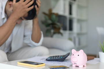 Stressed and headache man with large bills or invoices no money to pay to expenses and credit card...