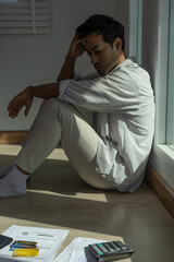 Stressed and headache asian man with large bills or invoices no money to pay to expenses and credit...