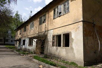 Old abandoned apartment building with broken windows and cracked walls in a residential area