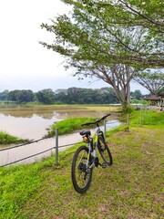 Obraz premium Mountain Bike Resting Beside a Calm Lake Under a Cloudy Sky, Nature Scene