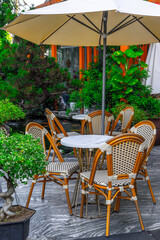 Cozy outdoor café seating with wicker chairs and umbrella in lush garden setting
